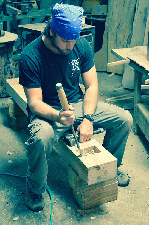 Adam chiseling out a mortar in a large beam for timber framing